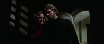 Movie still from “The House by the Cemetery” (1981), directed by Lucio Fulci – A man and a woman standing next to each other in the dark; Medium shot, Low angle