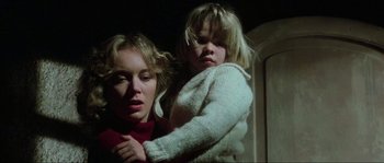 Movie still from “The House by the Cemetery” (1981), directed by Lucio Fulci – A woman holding a child in her arms; Close Up shot, Low angle