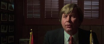 Movie still from “The House by the Cemetery” (1981), directed by Lucio Fulci – A man in a suit and tie sitting in front of a window; Close Up shot, Low angle