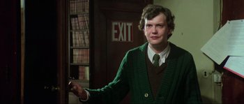 Movie still from “The House by the Cemetery” (1981), directed by Lucio Fulci – A man in a green sweater holding a remote control; Close Up shot, Over the shoulder angle