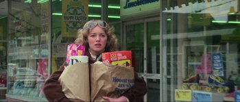 Movie still from “The House by the Cemetery” (1981), directed by Lucio Fulci – A woman holding a bag of food in front of a store; Medium shot, Low angle
