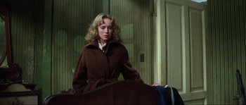 Movie still from “The House by the Cemetery” (1981), directed by Lucio Fulci – A woman wearing a brown coat standing in a room; Medium shot, Low angle