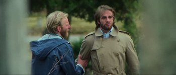 Movie still from “The House by the Cemetery” (1981), directed by Lucio Fulci – A man in a trench coat talking to another man in a blue jacket; Medium shot, Over the shoulder angle