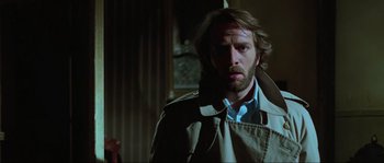 Movie still from “The House by the Cemetery” (1981), directed by Lucio Fulci – A man in a trench coat looking to his left; Close Up shot, Low angle