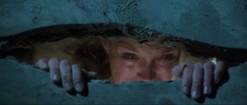 Movie still from “The House by the Cemetery” (1981), directed by Lucio Fulci – A woman looking through a hole in a wall; Close Up shot, Low angle