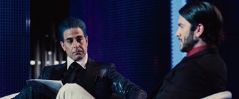 Movie still from “The Hunger Games” (2012), directed by Gary Ross – A man with blue hair and a suit and tie; Medium shot, Over the shoulder angle