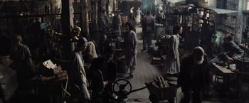 Movie still from “The Hunger Games” (2012), directed by Gary Ross – A group of people standing around a market area; Wide shot, High angle