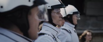 Movie still from “The Hunger Games” (2012), directed by Gary Ross – A group of people in white jackets and helmets; Close Up shot, Low angle