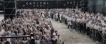Movie still from “The Hunger Games” (2012), directed by Gary Ross – A large group of people standing next to each other in front of train tracks; Extreme Wide shot, High angle