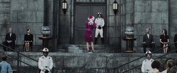 Movie still from “The Hunger Games” (2012), directed by Gary Ross – A man and a woman standing in front of a building; Wide shot, Low angle