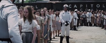 Movie still from “The Hunger Games” (2012), directed by Gary Ross – A group of people standing next to each other on a dirt road; Medium shot, Over the shoulder angle
