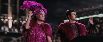 Movie still from “The Hunger Games” (2012), directed by Gary Ross – A man and a woman dressed up in a purple costume; Medium shot, Low angle