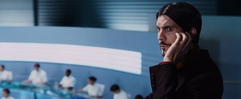 Movie still from “The Hunger Games” (2012), directed by Gary Ross – A man in a black suit is holding his hand up to his face; Close Up shot, Low angle