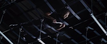 Movie still from “The Hunger Games” (2012), directed by Gary Ross – A person holding a knife in a dark room; Medium shot, Overhead angle