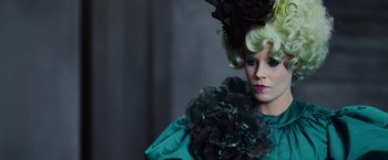 Movie still from “The Hunger Games” (2012), directed by Gary Ross – A woman in a green dress and a black hat; Close Up shot, Low angle