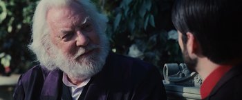 Movie still from “The Hunger Games” (2012), directed by Gary Ross – An old man with a beard sitting in a chair; Close Up shot, Over the shoulder angle