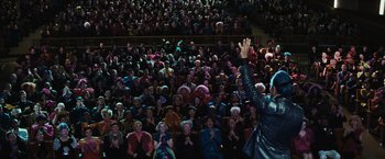 Movie still from “The Hunger Games” (2012), directed by Gary Ross – A crowd of people sitting and standing in front of a stage; Wide shot, High angle