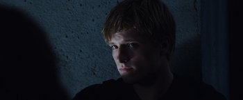 Movie still from “The Hunger Games” (2012), directed by Gary Ross – A man with blonde hair and blue eyes stares into the camera; Close Up shot, Low angle