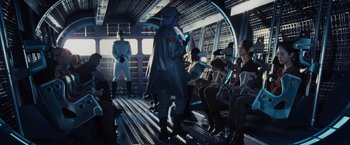 Movie still from “The Hunger Games” (2012), directed by Gary Ross – A group of people sitting in a room; Wide shot, Over the shoulder angle