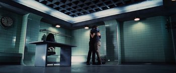 Movie still from “The Hunger Games” (2012), directed by Gary Ross – A man and a woman hugging in a room; Wide shot, Low angle