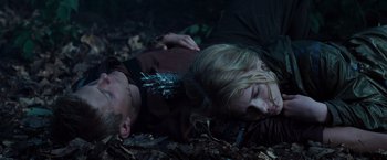 Movie still from “The Hunger Games” (2012), directed by Gary Ross – A man and a woman laying on the ground in the woods; Medium shot, Overhead angle