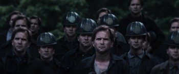 Movie still from “The Hunger Games” (2012), directed by Gary Ross – A group of men wearing helmets standing next to each other; Close Up shot, Over the shoulder angle