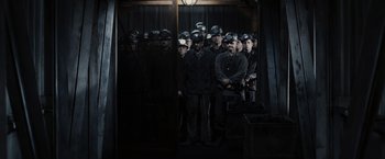 Movie still from “The Hunger Games” (2012), directed by Gary Ross – A group of men standing next to each other in a room; Extreme Wide shot, High angle