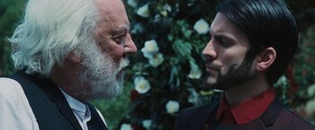 Movie still from “The Hunger Games” (2012), directed by Gary Ross – Two men are facing each other in front of flowers; Close Up shot, Over the shoulder angle