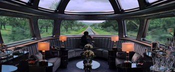 Movie still from “The Hunger Games: Catching Fire” (2013), directed by Francis Lawrence – A woman sitting on a couch looking out of a window; Wide shot, High angle