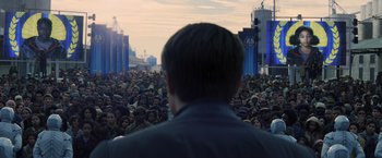 Movie still from “The Hunger Games: Catching Fire” (2013), directed by Francis Lawrence – A crowd of people standing in front of a man in a crowd; Wide shot, Over the shoulder angle