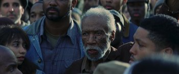 Movie still from “The Hunger Games: Catching Fire” (2013), directed by Francis Lawrence – An old man with a beard and a mustache is in a crowd of people; Close Up shot, High angle