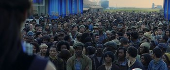 Movie still from “The Hunger Games: Catching Fire” (2013), directed by Francis Lawrence – A large group of people standing in front of a building; Wide shot, High angle