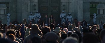 Movie still from “The Hunger Games: Catching Fire” (2013), directed by Francis Lawrence – A group of people sitting in front of a building; Wide shot, High angle