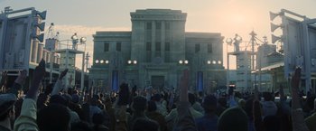 Movie still from “The Hunger Games: Catching Fire” (2013), directed by Francis Lawrence – A crowd of people standing in front of a large building; Extreme Wide shot, Low angle
