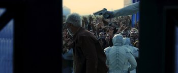 Movie still from “The Hunger Games: Catching Fire” (2013), directed by Francis Lawrence – An old man is walking through a crowd of people; Medium shot, Over the shoulder angle