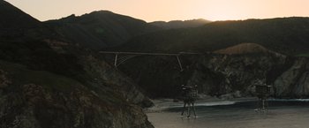 Movie still from “The Hunger Games: Catching Fire” (2013), directed by Francis Lawrence – A person standing in front of a bridge on a beach; Extreme Wide shot, Low angle