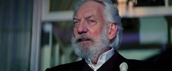Movie still from “The Hunger Games: Catching Fire” (2013), directed by Francis Lawrence – An older man with white hair and a white beard; Close Up shot, Low angle