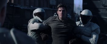 Movie still from “The Hunger Games: Catching Fire” (2013), directed by Francis Lawrence – A man is being restrained by another man; Medium shot, Over the shoulder angle