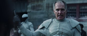 Movie still from “The Hunger Games: Catching Fire” (2013), directed by Francis Lawrence – A man in a white suit is standing next to another man in a white suit; Close Up shot, Low angle