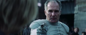 Movie still from “The Hunger Games: Catching Fire” (2013), directed by Francis Lawrence – An older man with a gun in his hand; Close Up shot, Over the shoulder angle