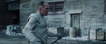 Movie still from “The Hunger Games: Catching Fire” (2013), directed by Francis Lawrence – A man in a white suit is holding a sword; Medium shot, Over the shoulder angle