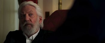 Movie still from “The Hunger Games: Catching Fire” (2013), directed by Francis Lawrence – An old man with a white beard sitting in a chair; Close Up shot, Over the shoulder angle