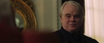 Movie still from “The Hunger Games: Catching Fire” (2013), directed by Francis Lawrence – Philip seymour hoffman wearing a suit; Close Up shot, Over the shoulder angle