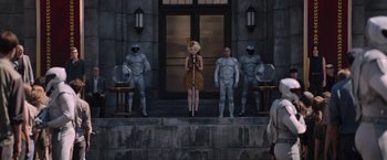 Movie still from “The Hunger Games: Catching Fire” (2013), directed by Francis Lawrence – A woman standing in front of a group of people; Wide shot, Low angle