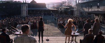 Movie still from “The Hunger Games: Catching Fire” (2013), directed by Francis Lawrence – A crowd of people are gathered in front of an outdoor stage; Extreme Wide shot, High angle