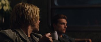 Movie still from “The Hunger Games: Catching Fire” (2013), directed by Francis Lawrence – Two men sitting in front of each other holding a cup; Close Up shot, Over the shoulder angle
