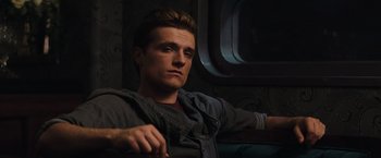 Movie still from “The Hunger Games: Catching Fire” (2013), directed by Francis Lawrence – A man sitting on a couch in a dark room; Close Up shot, Low angle