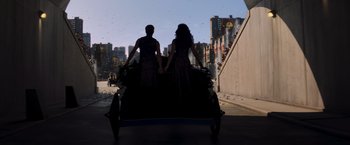 Movie still from “The Hunger Games: Catching Fire” (2013), directed by Francis Lawrence – Two people holding hands while sitting on a carriage; Wide shot, Low angle