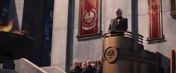 Movie still from “The Hunger Games: Catching Fire” (2013), directed by Francis Lawrence – A group of people sitting in front of a podium; Extreme Wide shot, Low angle