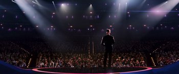 Movie still from “The Hunger Games: Catching Fire” (2013), directed by Francis Lawrence – A man standing in front of an audience on a stage; Extreme Wide shot, High angle